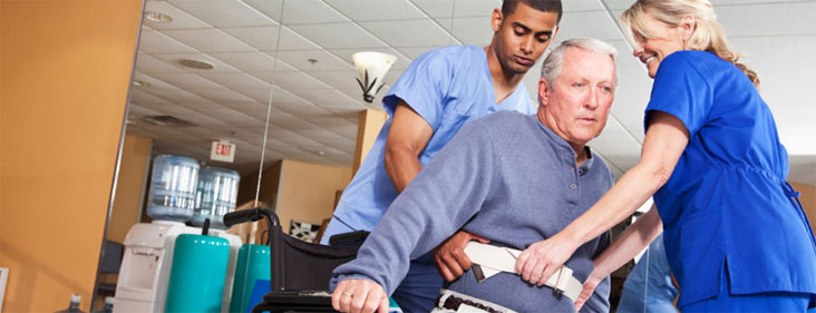 elderly man in chair being assisted by two nurses