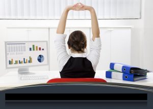 Lady sitting at desk with arms stretched high.