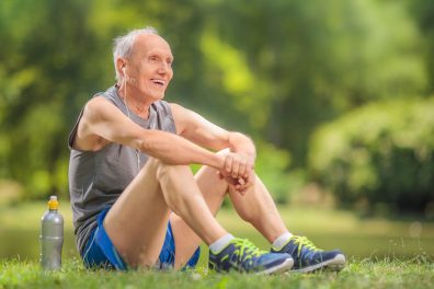 Athletic senior in sportswear sitting on grass in a park