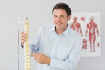 Osteopath trainer pointing at model of a spine