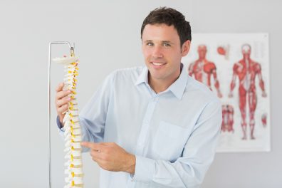 Osteopath trainer pointing at model of a spine