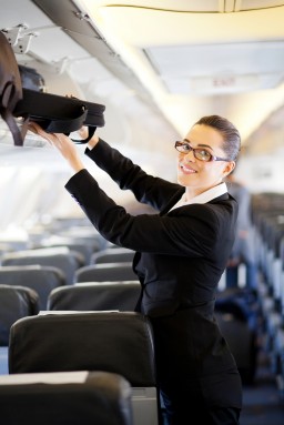 Lady using Manual Handling to stow overhead luggage on a plane